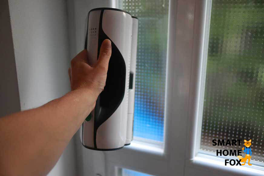 Man sieht, wie ein besonders schmales Fenster mit dem Vorwerk Kobold VG100 gesäubert wird.